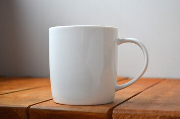 White cup with coffee on a wooden background.