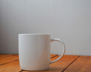 Obraz premium White cup with coffee on a wooden background.