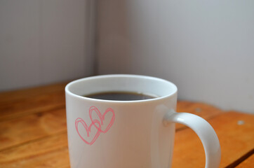 White cup with coffee on a wooden background.