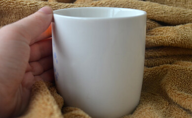 White mug with coffee and steam on a brown plaid, book, notebook