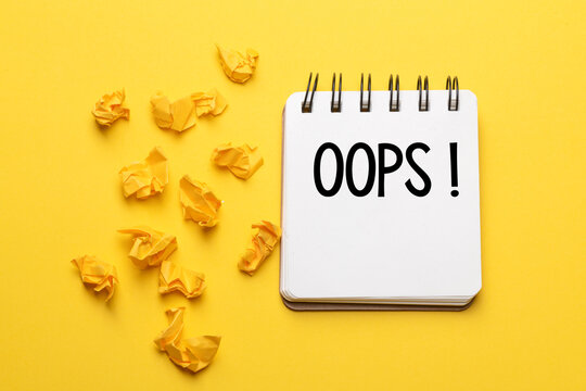 The words Oops with a black marker in a notebook on a yellow background .. Apologies for a minor accident or mistake.