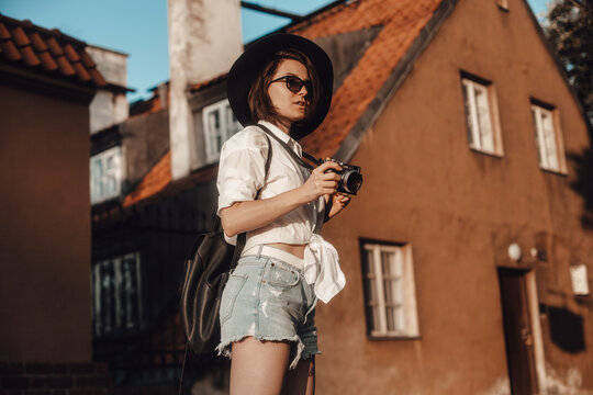 Young hipster girl with a camera in an old European city. The girl is traveling
