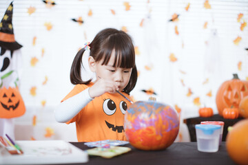 young girl painting pumpkin for halloween party at home
