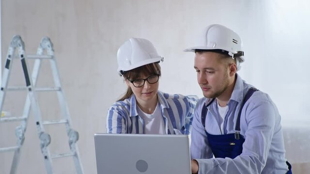 working team, young friendly specialists designers builders male and female with color scheme in their hands discussing new modern renovation for room using project on laptop