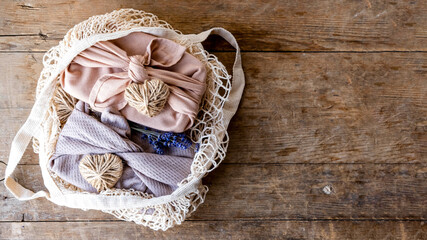  valentine's day gift packed in furoshiki style. festive layout on wooden background. Zero waste Valentine's Day concept and mock up. with lavender, jute hearts