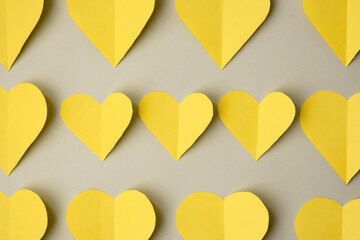 yellow hearts cut out of colored paper on a gray background, top view, colors 2021. Trendy colored valentines day concept.