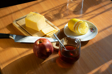 Breakfast. Mug of tea and sliced ​​cheese, apple and lemon on cutting board
