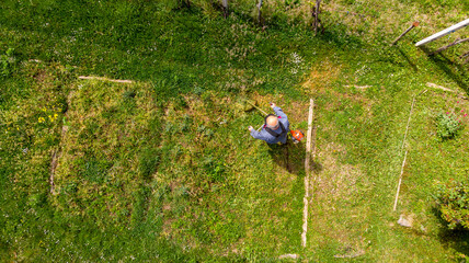 Drop down view of a person mowing lawn.