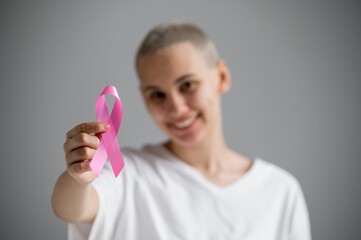 Young woman with pink ribbon on a white background. Mammary cancer