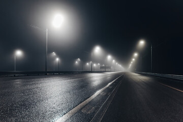 Foggy misty night road illuminated by street lights