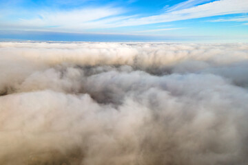 Aerial view from above of white puffy clouds in bright sunny day.
