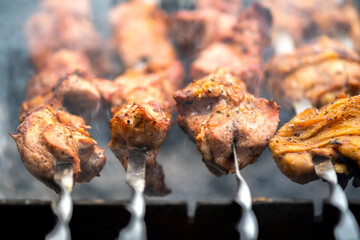 Shashlik or shish kebab preparing on barbecue grill over hot charcoal. Grilled pieces of pork meat on metal skewers.