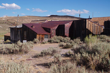 Abandoned buildings at the abandoned Bodie ghost town in the Sierra Nevada mountains of California on a sunny day with clouds