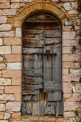 Fototapeta na wymiar Old wooden door of a medieval palace in the ancient village of Spello, in Umbria (Italy)