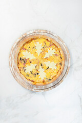 New year style pizza served on wooden board. Kids food. Pizza decorated with holiday Christmas cheese trees. Served with pesto sauce. Pizza with Cheesy Snowflake on top. Marble background 
