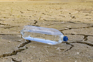 A bottle of water on the dried ground. 
The concept of thirst, dehydration.
