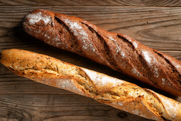 Crispy wheat and buckwheat baguettes on rustic wooden background.