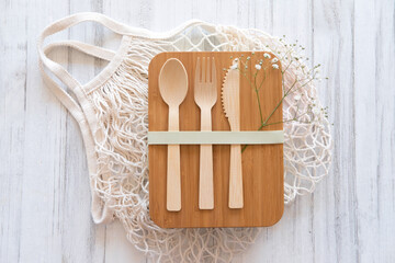 Fototapeta na wymiar Set of cutlery (fork, spoon, knife) made of wood or bamboo, bamboo reusable lunch box. Zero waste concept. Pink background. Top view. 