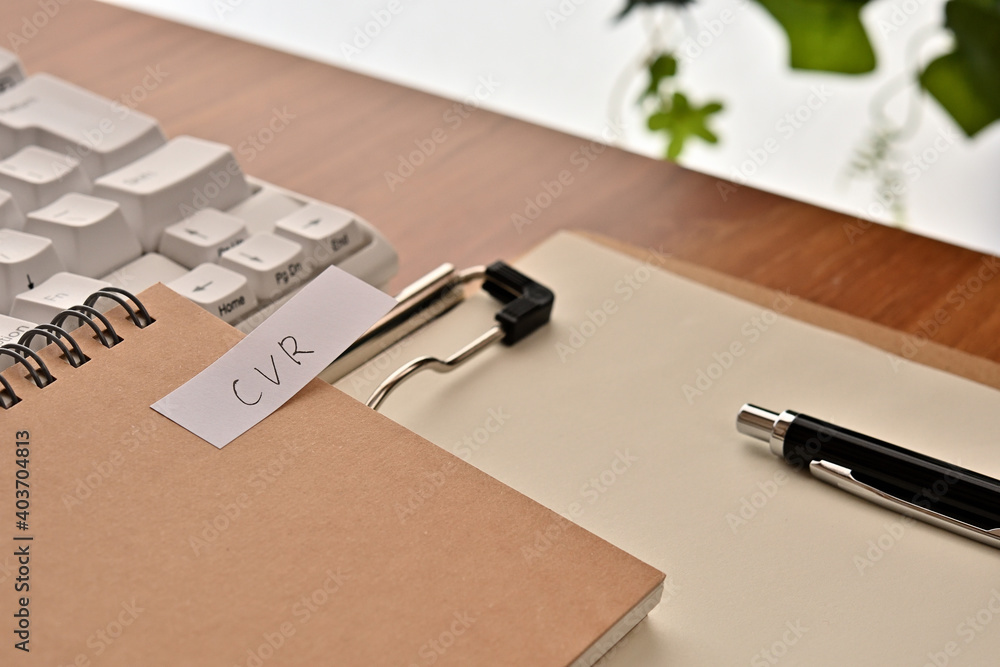 Poster a sticky note labeled cvr is taped to the edge of a notebook on the desk.that's an acronym for conve
