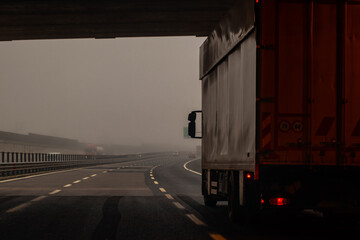 Truck or lorry just getting out of a tunnel on a foggy motorway. Dangerous ride with a truck.
