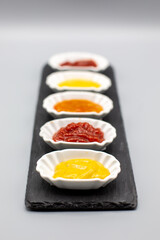 Various dips and sauces on slate slab with white background