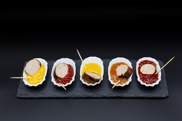 small try-out plates with bratwurst, currywurst and other sausages plus various sauces and dips