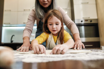 Fototapeta premium Granddaughter and grandmother preparing dough for home baking