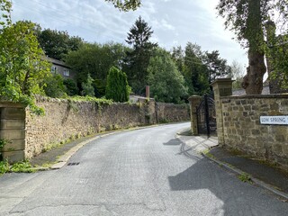 Fototapeta na wymiar Looking up, Thwaites Brow Road, with high stone walls, and trees in, Thwaites, Keighley, UK