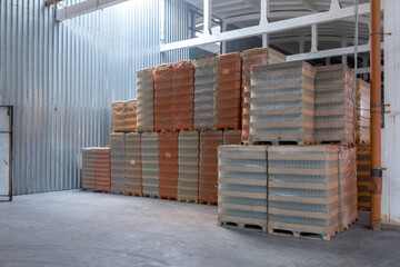 The storage and carriage at industrial food industry facility. A glass clear bottles for alcoholic or soft drinks beverages and canning jars stacked on pallets for forklift.