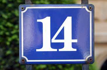 A blue house number plaque, showing the number fourteen (14)

