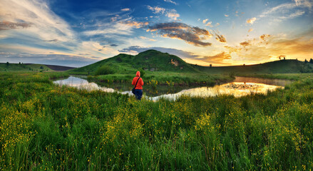 woman on the banks of the picturesque river. tourist is enjoying the morning landscape. colorful spring sunrise