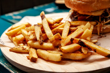 Tasty French fries on wooden plate ready to eat