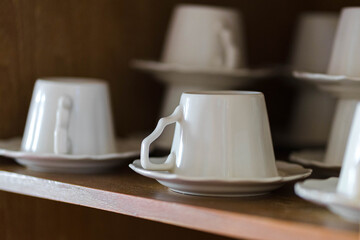 Ceramic cups are neatly stored in a wooden cupboard.
