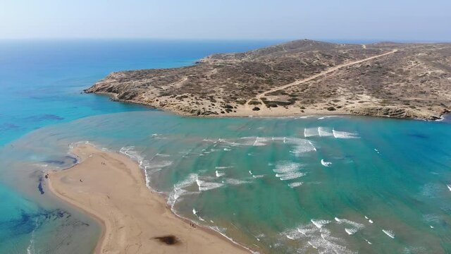 Scenic drone footage of Prasonisi peninsula in Rhodes in Greece surrounded by turquoise water. Kitesurfing and windsurfing. Waves on the Aegean Sea and calm flat water on the Mediterranean Sea.