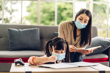 Portrait love asian family mother and little asian girl learning and writing in book with pencil making homework in quarantine for coronavirus wearing protective mask with social distancing at home