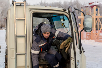 Naklejka premium Portrait of a fitter in a blue jacket near the car cab