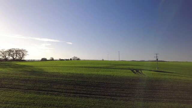 Ascending drone shot of rolling green fields and blue skies