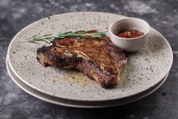 Grilled red beef pork meat barbecue steak fillet with rosemary sprig and hot sauce served on plate