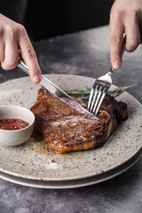 Person cuts Juicy Grilled red beef pork meat barbecue steak fillet with rosemary sprig
