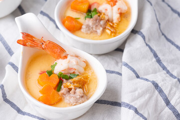 Homemade style steamed egg with shrimp and vegetables in a ceramic bowl on wooden table. healthy food concept.