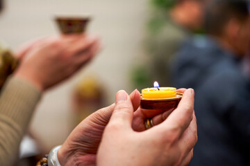 People holding small candle holders in the blessing