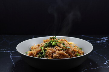 Fried and stirred spicy rice noodle with traditional sauce and seasoning with spring onion and pepper. 