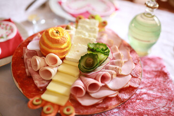 Food tray with delicious salami, pieces of sliced ham and yellow cheese