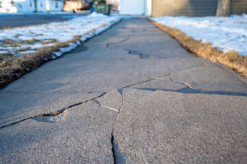 Frost heave crack in residential concrete sidewalk - Powered by Adobe