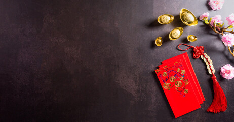Chinese new year festival decorations pow or red packet, orange and gold ingots on dark stone background. Chinese characters FU in the article refer to fortune good luck, wealth, money flow.