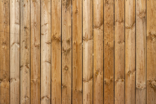 Full frame texture background of a wooden fence with natural wood grain planks, in bright sunlight