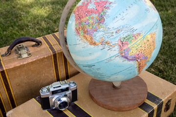 Globe and Camera on a Suitcase with Another Suitcase in the Back