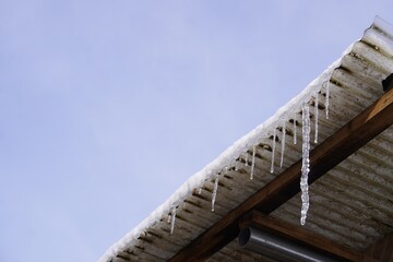 トタン屋根から垂れる大きなつらら/An icicles have formed under the iron roof