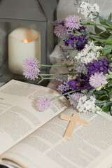 Purple Flowers, Lantern, and a Wooden Cross on an Open Bible