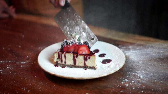 Chef throw sugar flour to cheesecake with butcher knife slow motion